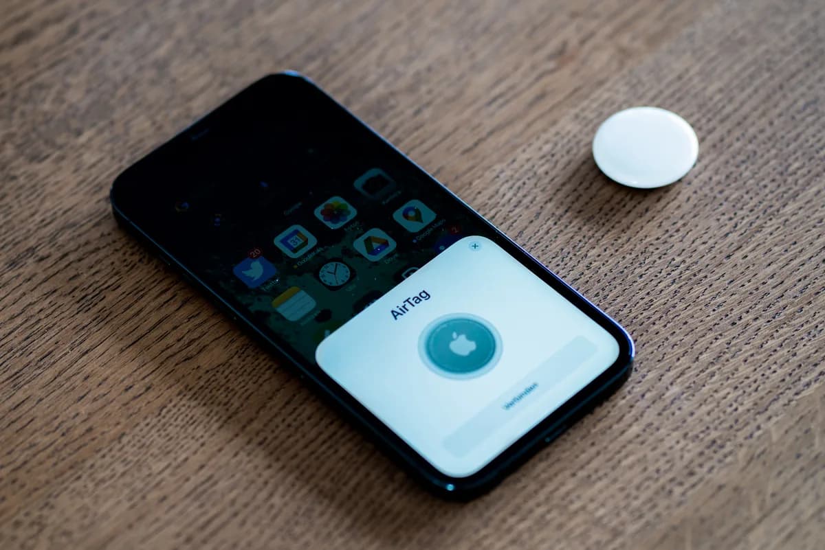 Apple AirTag blanc à côté d’un téléphone pendant sa configuration